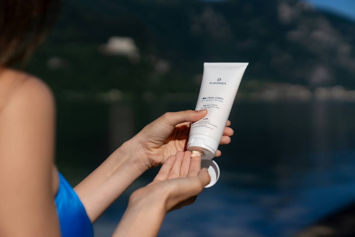 Woman applying vitamin b for skin care enriched body sunscreen at the beach